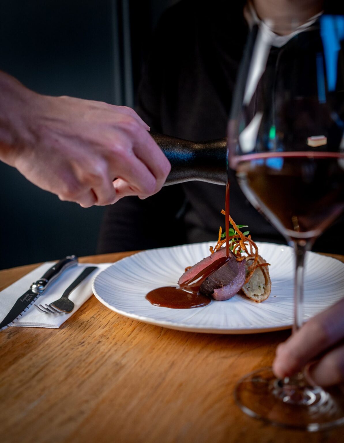 Vleesgerecht met saus en een glas rode wijn bij Restobar Saluut