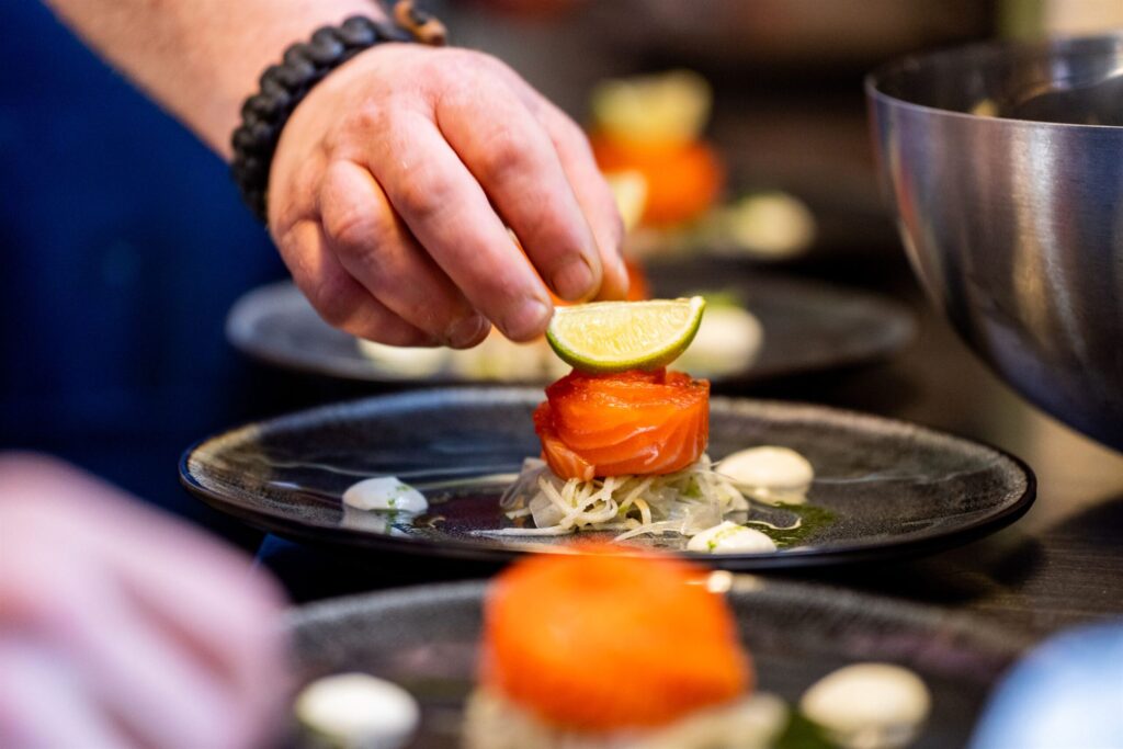 Kok maakt een gerecht met zalm en limoen op in de keuken van Restobar Saluut
